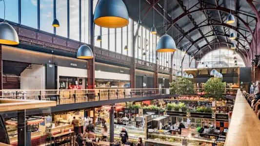 Interior de um mercado com bancas e luminárias suspensas